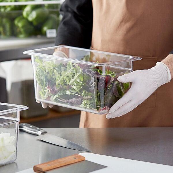 A person in a chef's uniform holding a Choice clear plastic food pan of salad.