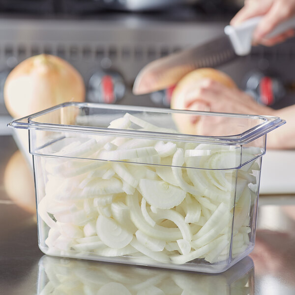 A person cutting onions in a Choice clear plastic food pan.