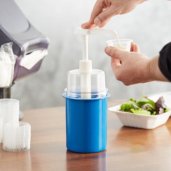 A person pouring liquid into a blue Steril-Sil condiment dispenser on a table.