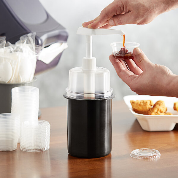 A person pouring liquid into a container from a black Steril-Sil condiment dispenser.