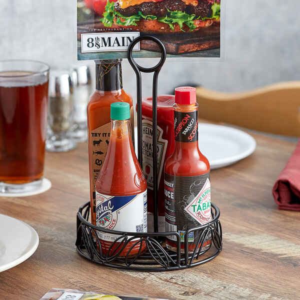 An American Metalcraft wrought iron condiment caddy holding hot sauces on a table.