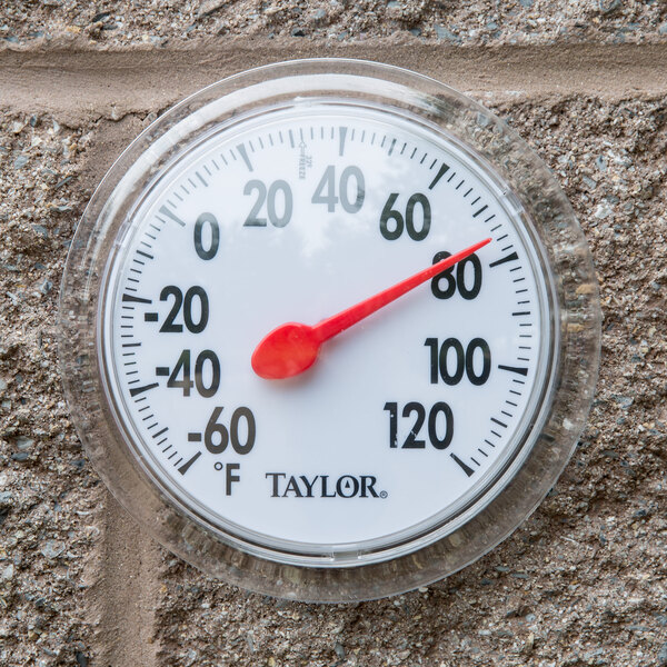 A Taylor 5630 wall thermometer on a brick wall.