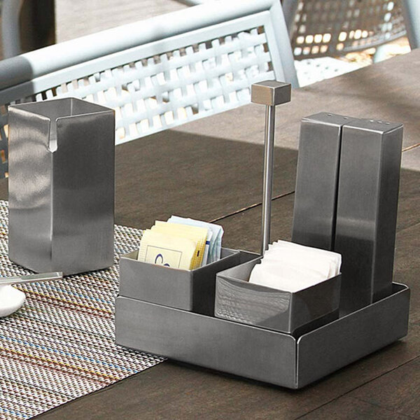 A metal container with a Front of the House brushed stainless steel condiment caddy on a table.