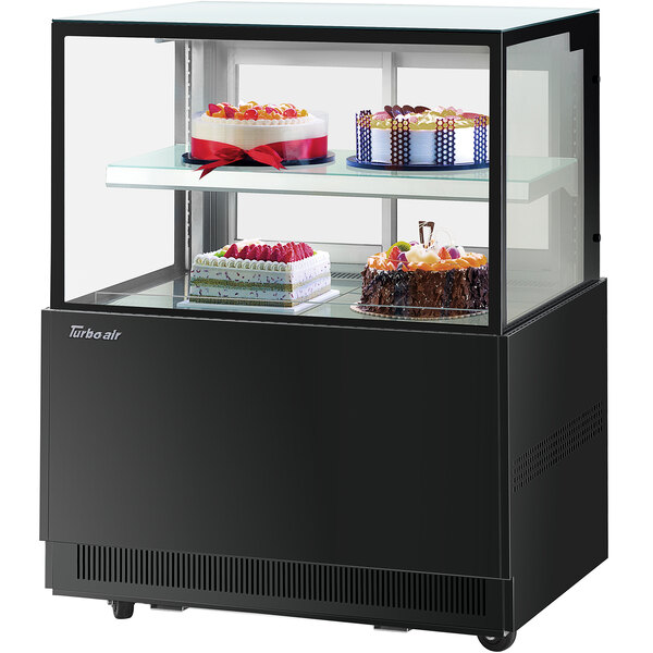 A Turbo-Air black refrigerated bakery display case with cakes on it.