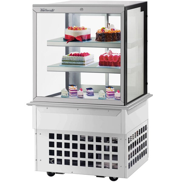 A Turbo-Air glass display case with cakes on it.