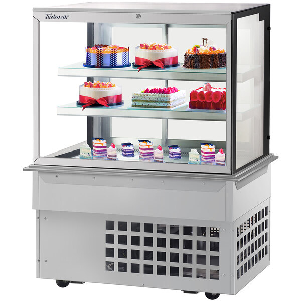 A Turbo-Air refrigerated bakery display case with cakes on it.