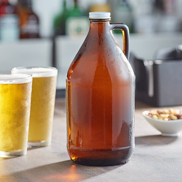 A close up of an Acopa amber growler filled with beer next to two glasses of beer.