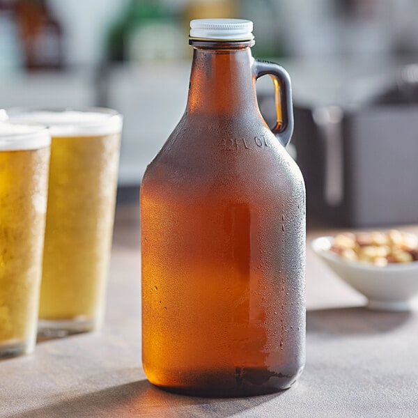 A close-up of an amber Acopa beer growler with cap next to two glasses of beer.