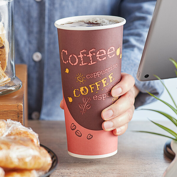 A person holding a Choice Coffee Print Poly Paper Hot Cup with a pastry.