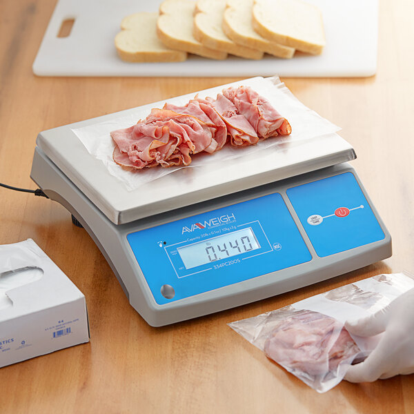 An AvaWeigh digital portion scale on a counter with meat and bread on it.