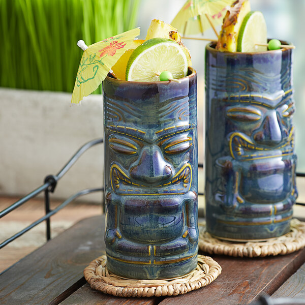 Two blue Tuxton ceramic tiki mugs filled with fruit and umbrellas.