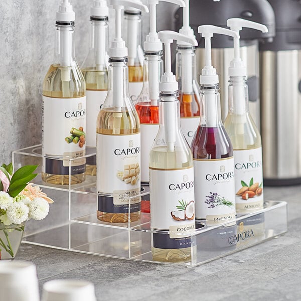 A Capora 3 tier syrup bottle organizer holding bottles of liquid on a counter.