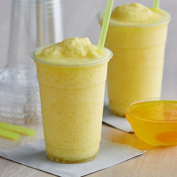 Two cups of Bossen pineapple smoothie with straws and green lids.
