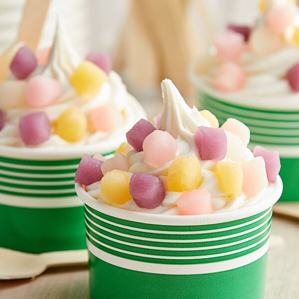 A group of green cups with assorted mini mochi rice cakes on top.
