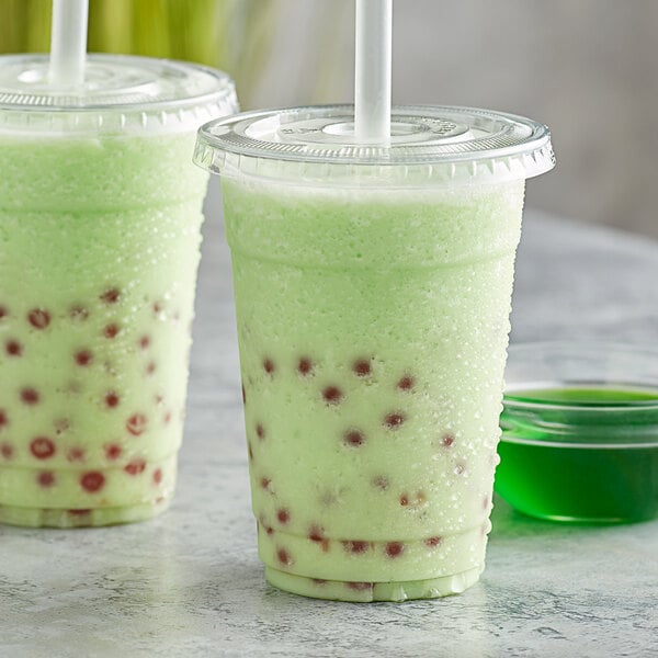 Two plastic cups of Bossen Honeydew green drinks with straws.