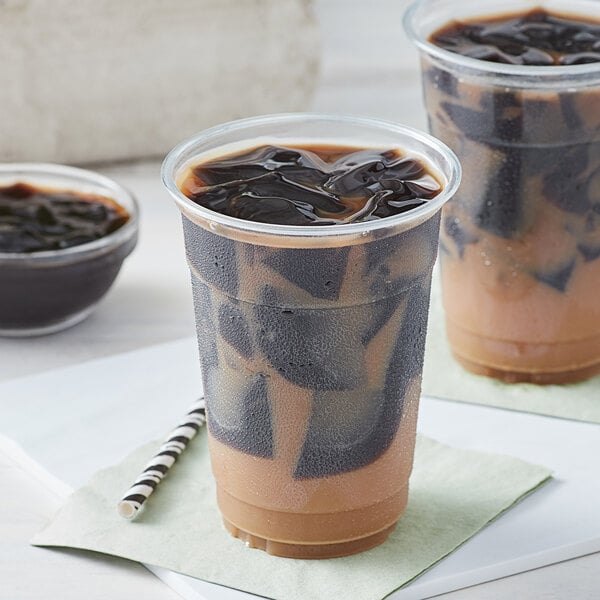 Two plastic cups of iced coffee with Bossen grass jelly liquid and black straws.