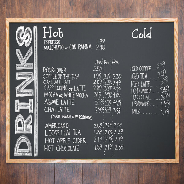 An Aarco oak-framed chalkboard menu with white writing on it.