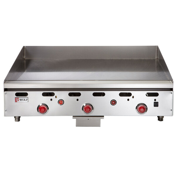 A Wolf stainless steel liquid propane griddle with red knobs.