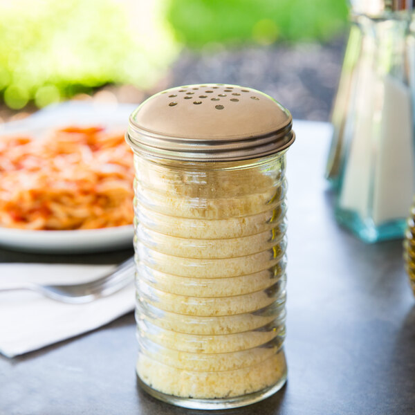 A Tablecraft beehive cheese shaker with a stainless steel lid on a table with food.