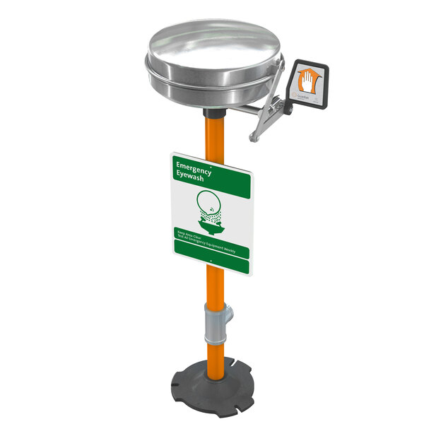 A Guardian Equipment pedestal mounted eyewash station with a stainless steel bowl and cover under a green and white sign.