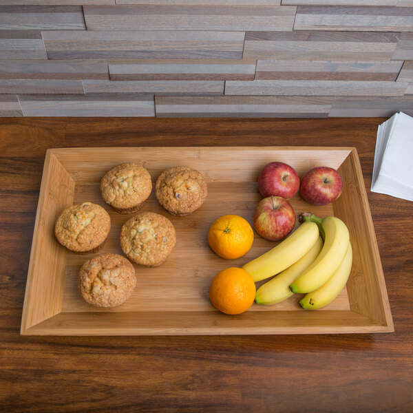 An American Metalcraft rectangular bamboo tray with a variety of fruit on a table.