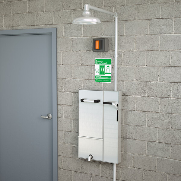 A grey Guardian Equipment safety station with a drain pan and a daylight drain on a grey wall.