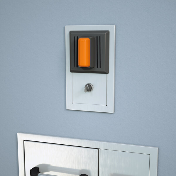A Guardian Equipment combination strobe light and alarm horn with a silencing switch on a wall above a door.