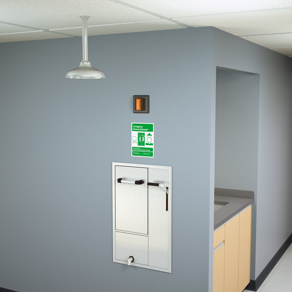 A white wall with a Guardian Equipment recessed safety station with a door and light fixture.