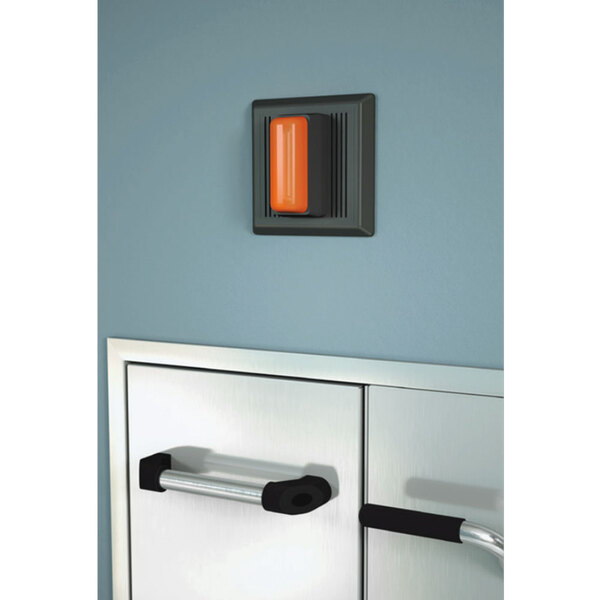 A black and orange Guardian Equipment strobe light and alarm horn on a wall.