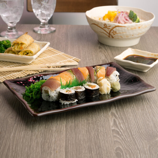 A rectangular black Thunder Group melamine plate with a sushi roll on it.
