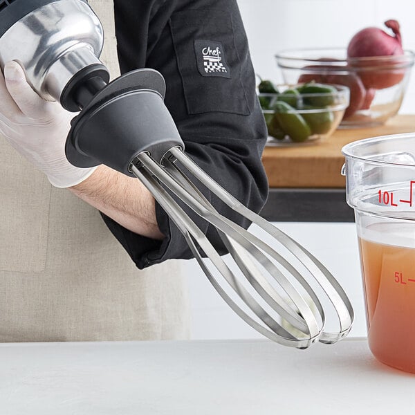A person using an AvaMix whisk attachment to mix a liquid.