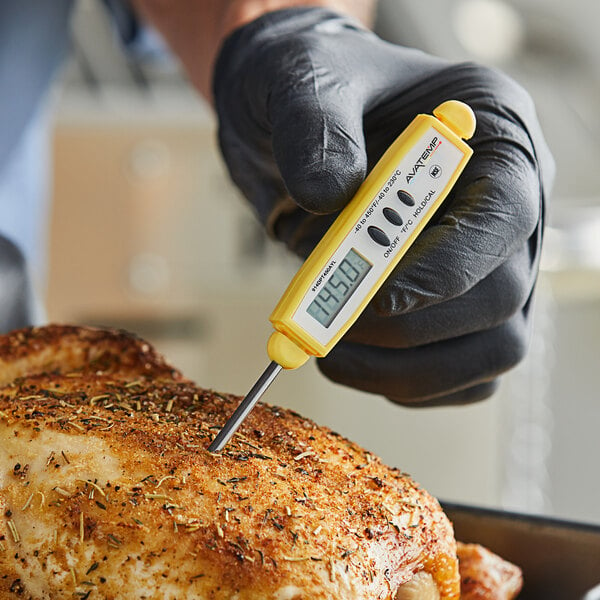 A person using a yellow AvaTemp digital pocket probe thermometer to measure the temperature of a chicken.
