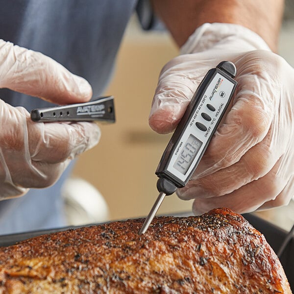 A person in gloves using an AvaTemp digital pocket probe thermometer to check the temperature of meat.