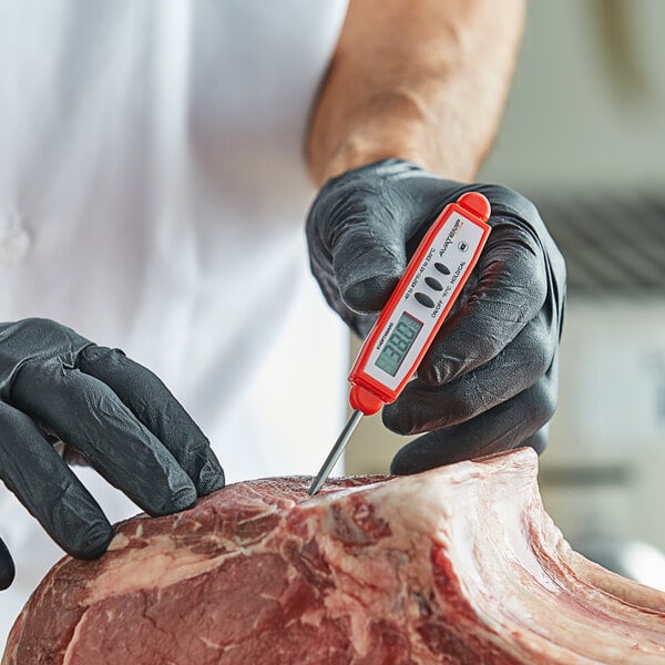 A person in gloves using a red AvaTemp digital pocket probe thermometer to measure raw meat.