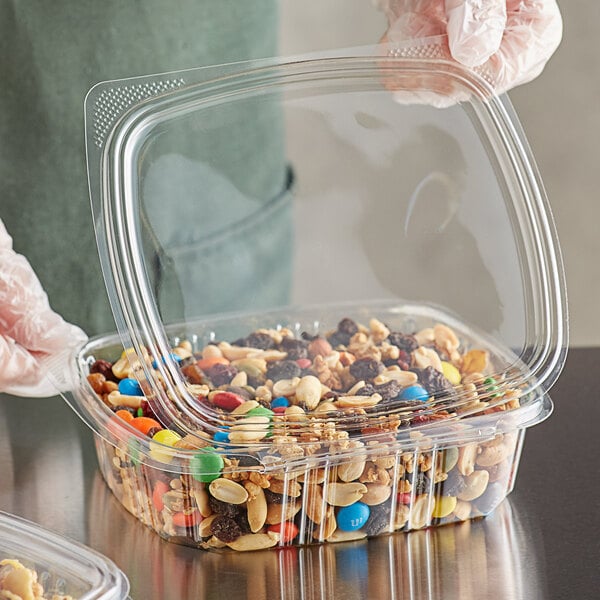 A person using a Choice clear plastic container to hold nuts and candy at a salad bar.