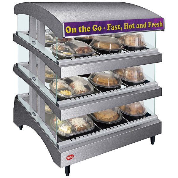A Hatco countertop heated display warmer with food trays on a display case.