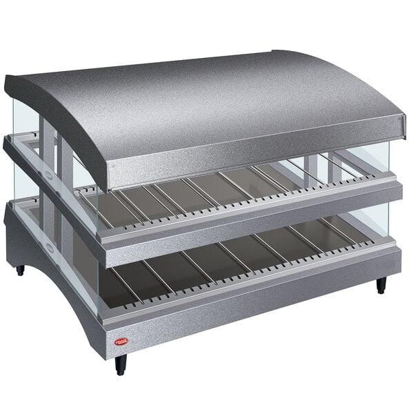 A Hatco countertop food warmer with double shelves and a curved glass top on a bakery counter.