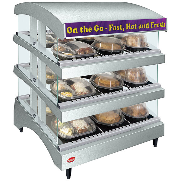 A Hatco white heated glass countertop food warmer with trays of food on display.