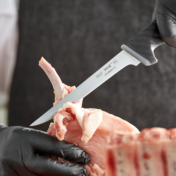 A person in black gloves using a Schraf narrow stiff boning knife with a TPRgrip handle to cut meat.