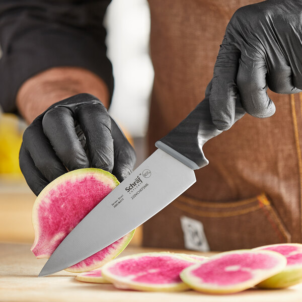 A person in black gloves using a Schraf chef knife to cut watermelon.