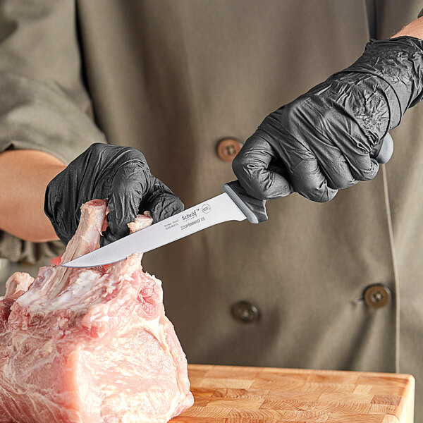 A person in black gloves using a Schraf Narrow Semi-Flexible Boning Knife to cut meat.
