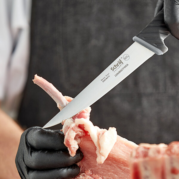 A person in black gloves using a Schraf boning knife to cut meat.