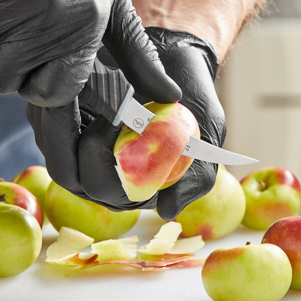 A person in black gloves using a Schraf Bird's Beak Paring Knife to peel a green apple.