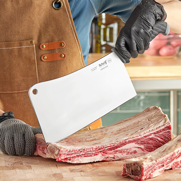 A person cutting meat with a Schraf meat cleaver.