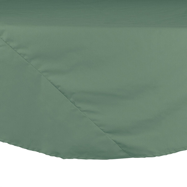 A seafoam green Intedge cloth table cover with a round top on a table.