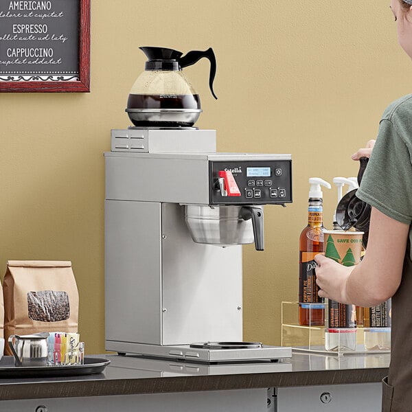 A woman pouring coffee from an Estella Caffe automatic coffee brewer.
