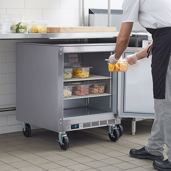 A man in a kitchen putting food into a Beverage-Air undercounter freezer.