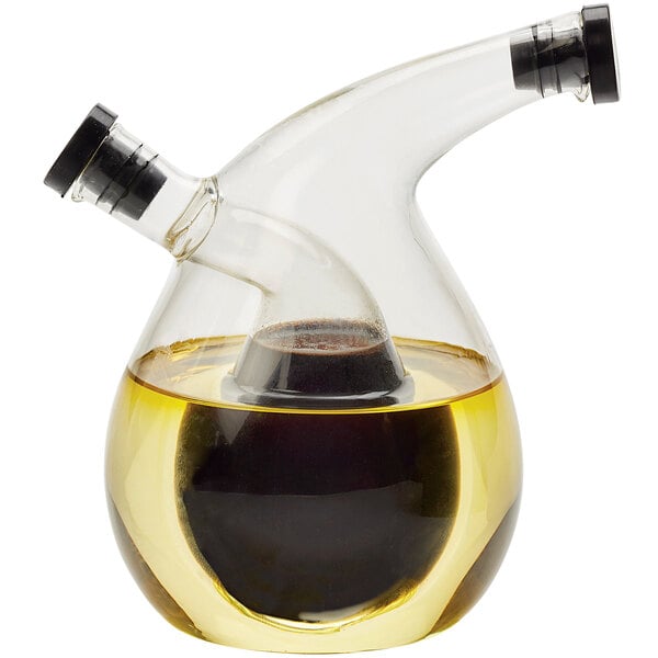 An American Metalcraft glass oil and vinegar cruet with brown and black liquid inside.