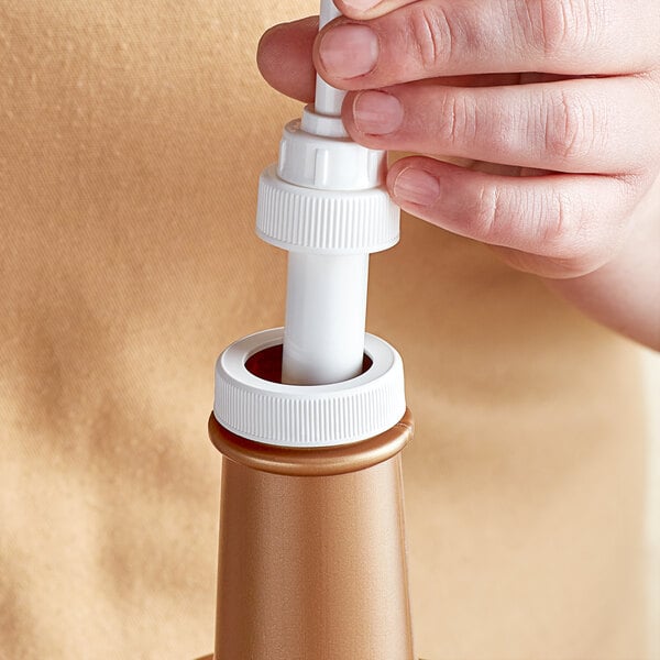 A person holding a white plastic bottle with a Tablecraft threaded adapter lid.