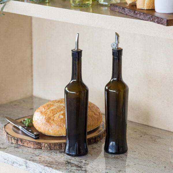 A pair of Tablecraft dark green glass oil and vinegar bottles on a counter.